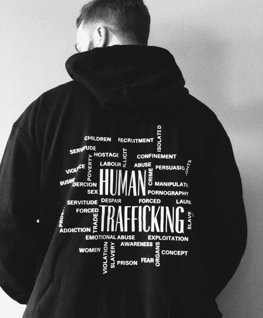 man facing away showing the back of his black hoodie with the word human trafficking on it